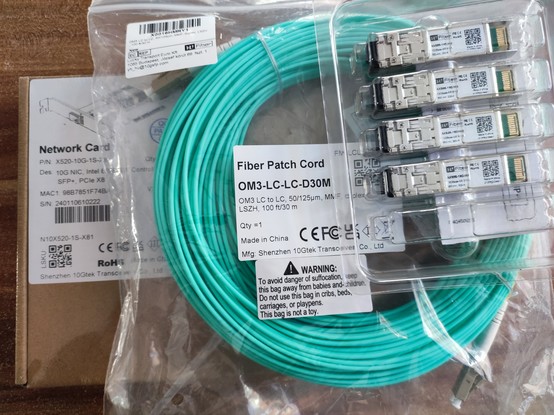 Verpacktes Netzwerk-Equipment. Eine PCI Express Karte mit SFP+ Käfig, 30m OM3 Glasfaser mit LC Stecker und 4x 10G SFP+ Module von H!Fiber.