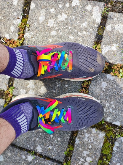 Schuhe von oben mit Regenbogen-Schnürsenkel.