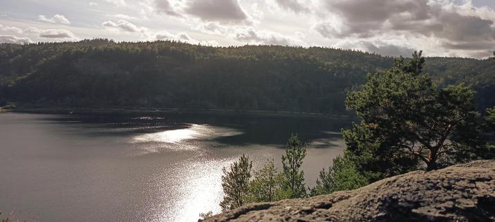 Blick über einen See von einem großen Stein aus. In der Ferne sind Wälder zu sehen. Blick über einen See von einem großen Stein aus. In der Ferne sind Wälder zu sehen.
